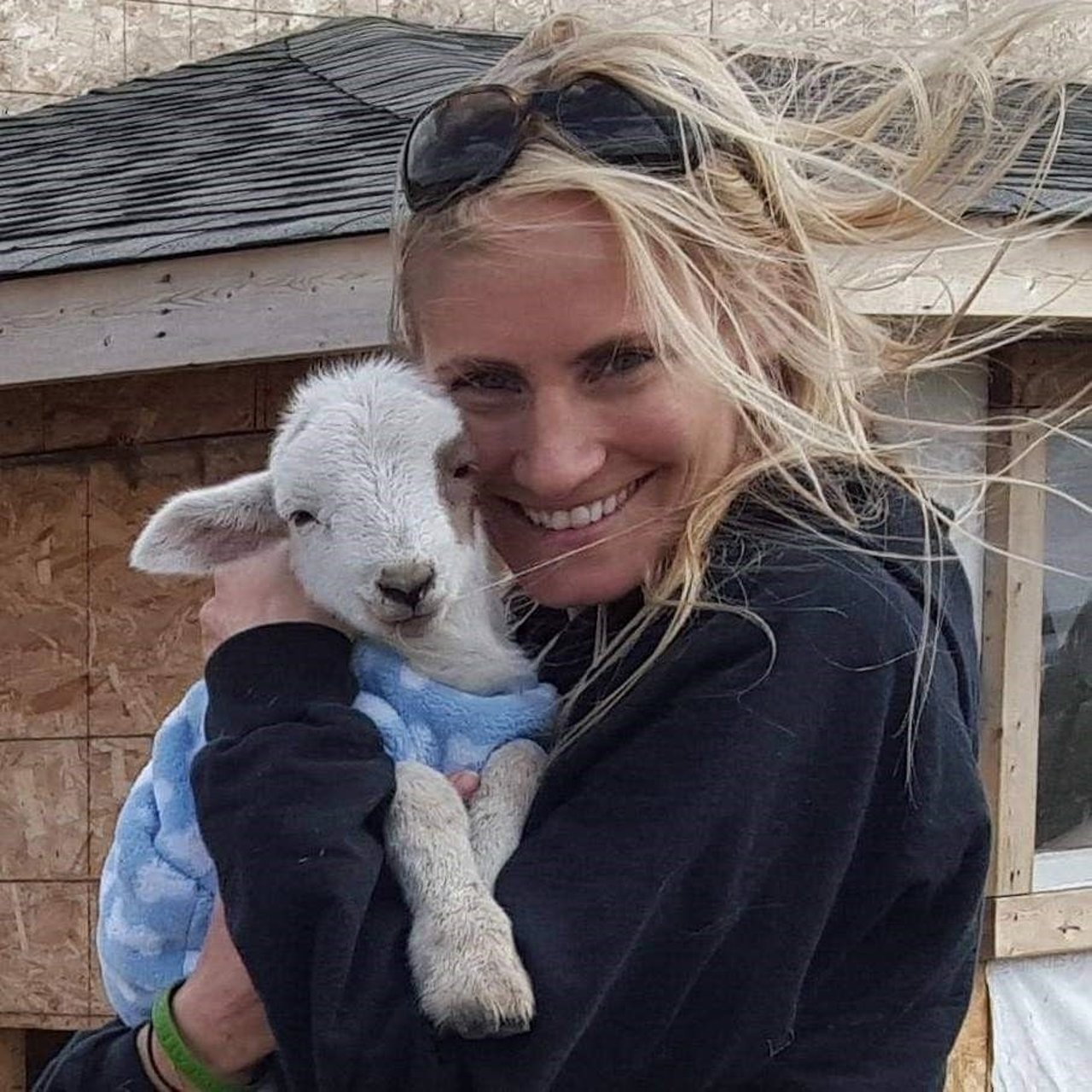 Lindsay Oliver Executive Director cuddling a lamb