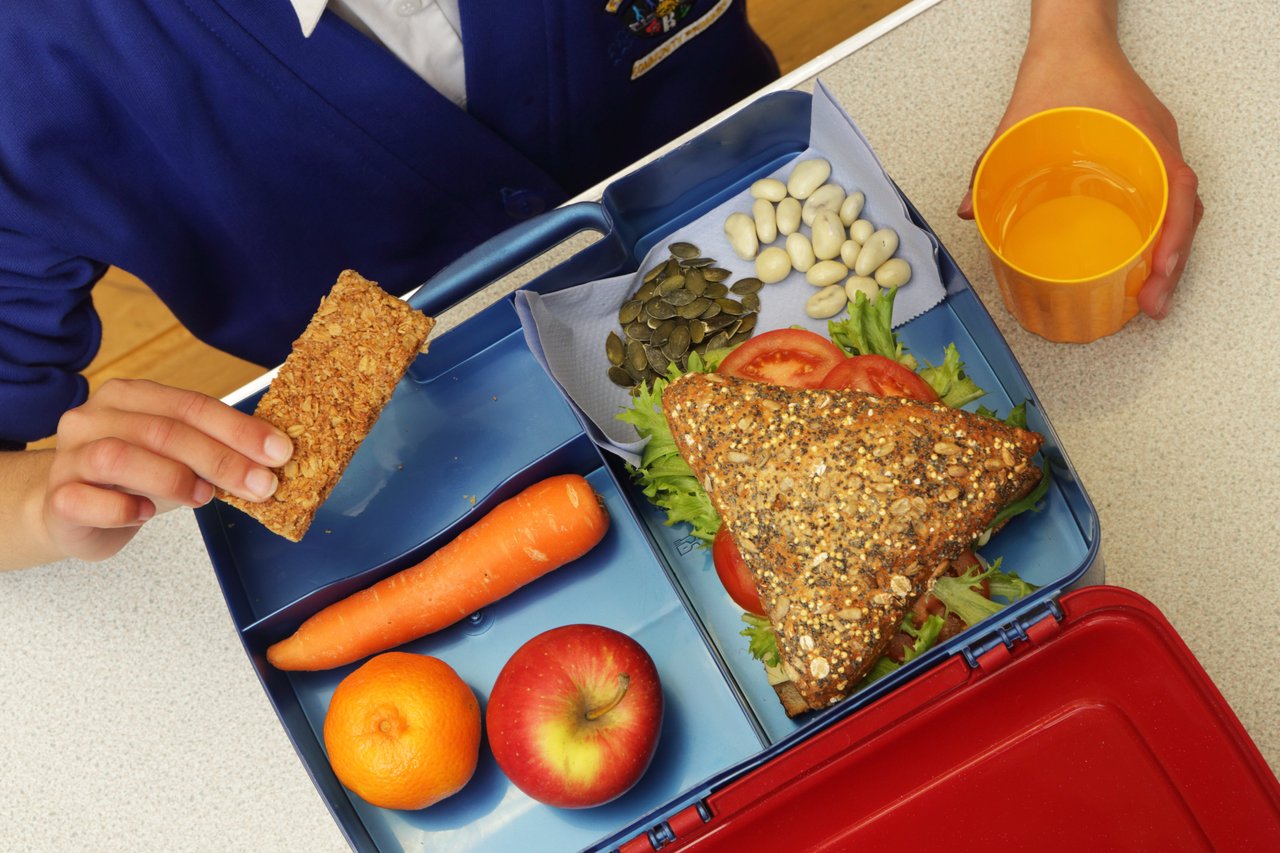 A child eating a healthy plant-based school lunch.