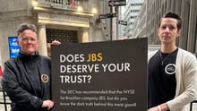 Interim US Executive Director Cameron Harsh and Global CEO Tricia Croasdell hold a sign outside of the New York Stock Exchange.