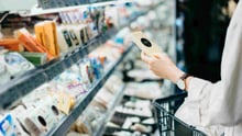 A person shopping for cheese at a grocery store.