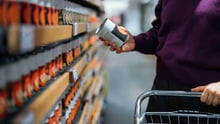 A person grocery shopping for a can of soup.