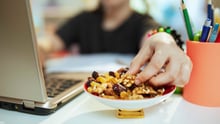 A college student snacking on trail mix while working on their laptop.