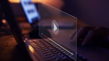 A composite image of a laptop with a computer window over top and a play button.