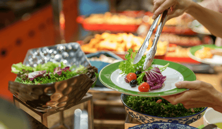 A vegan buffet, with one diner serving salad onto their plate.