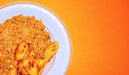 A bowl of red lentils overlayed on an orange background.