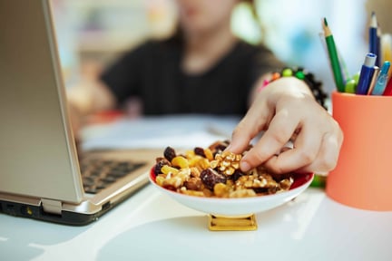 A college student snacking on trail mix while working on their laptop.