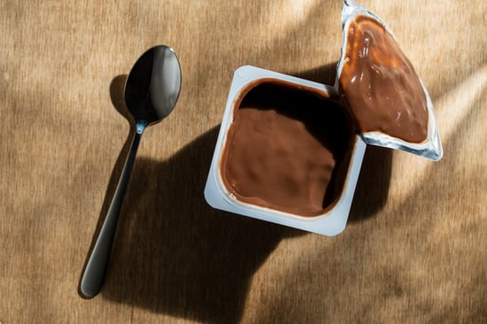 An open pudding snack pack with a spoon.