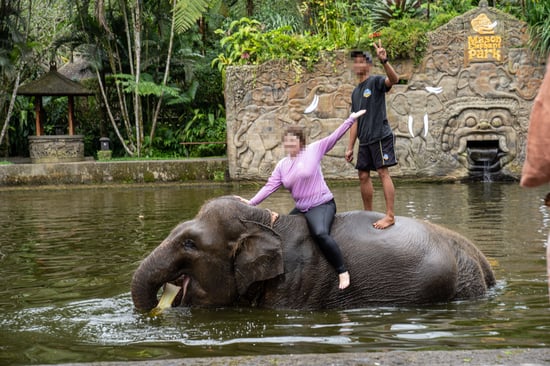 Two people riding an elephant.