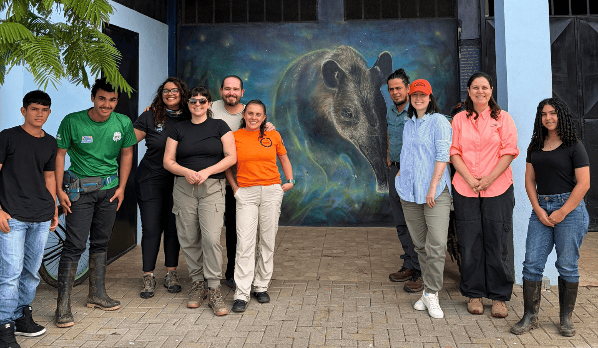 World Animal Protection staff gather with the Tapir Valley community leaders in front of a mural of a tapir.