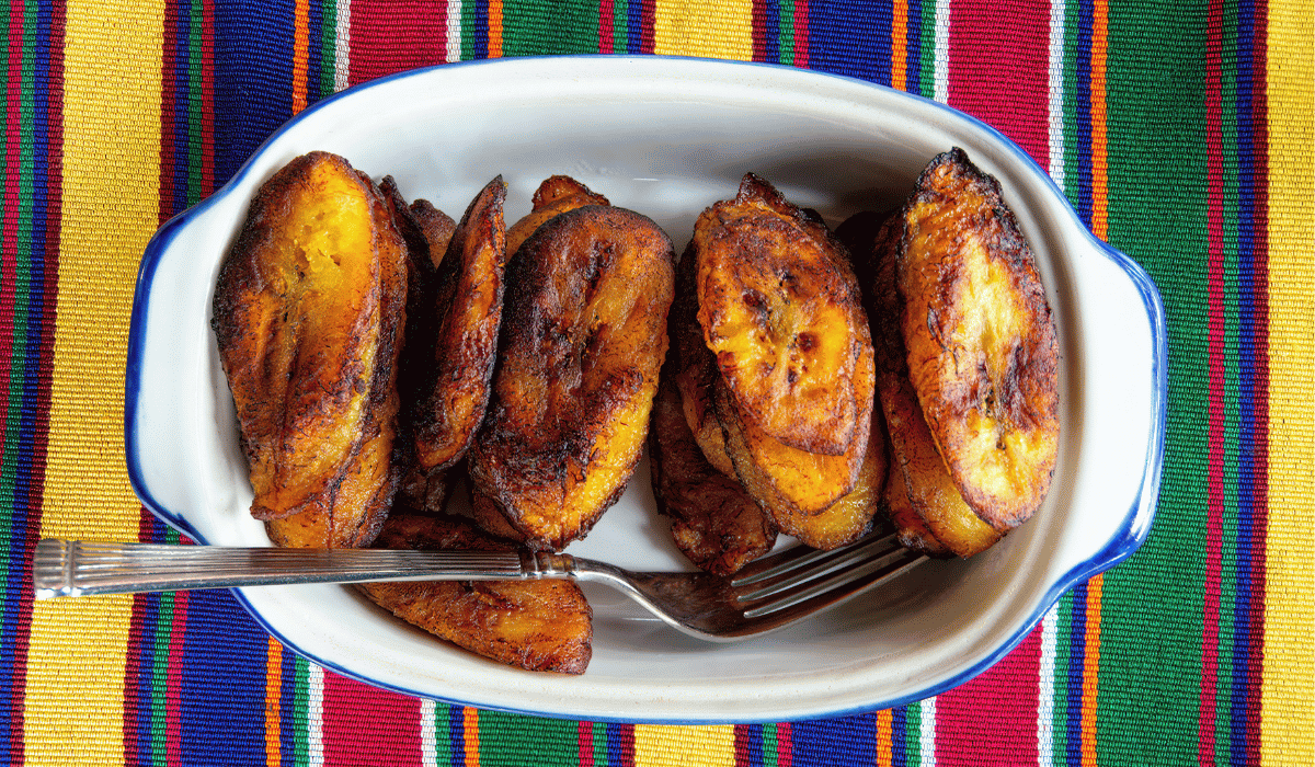 Fried plantains in a dish on a striped tablecloth.