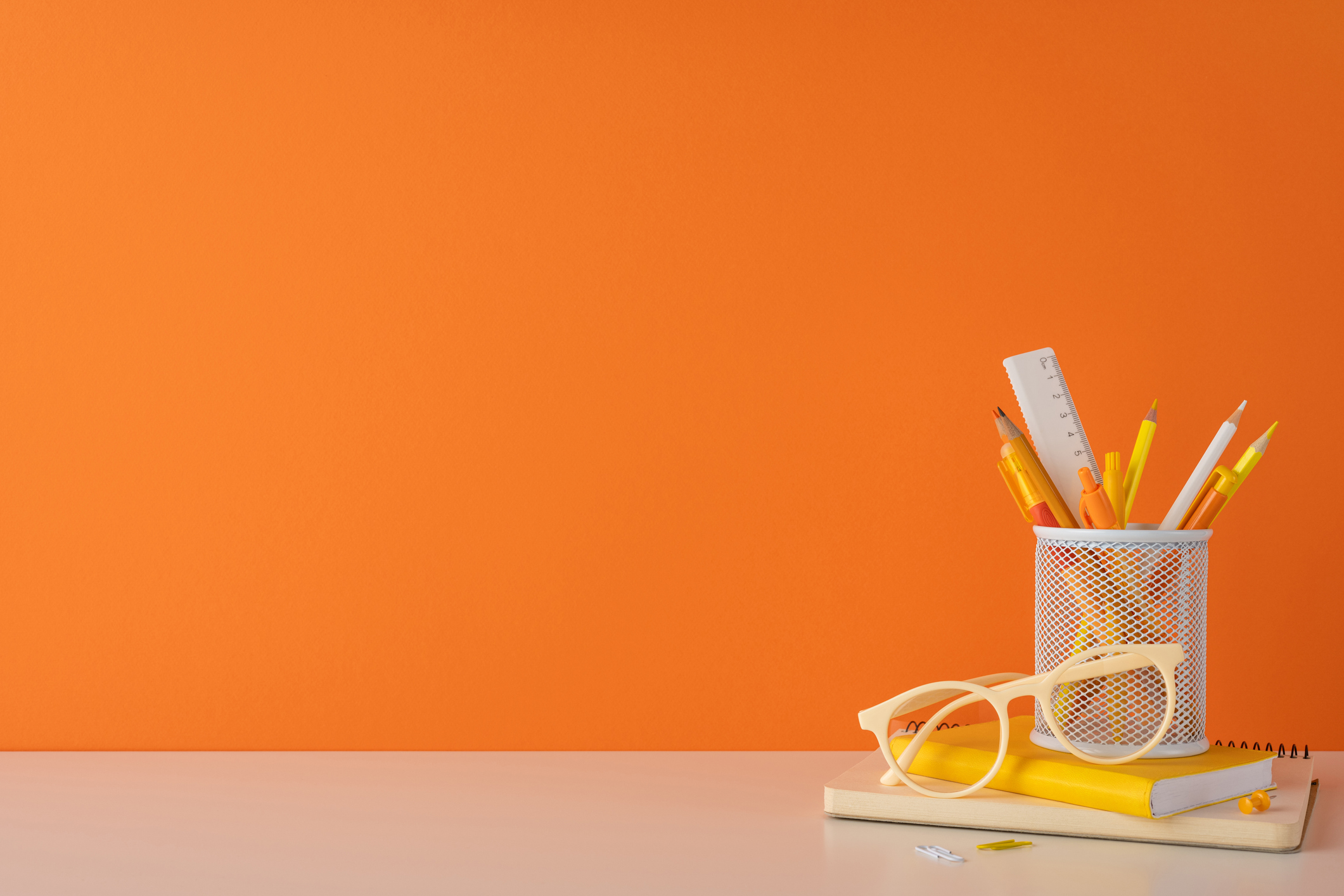 Orange background with school supplies on a desk.
